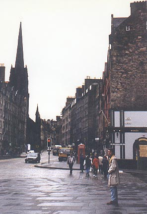 Andrew Lenz in a rain jacket standing on a wet street (Royal Mile, Edinburgh)