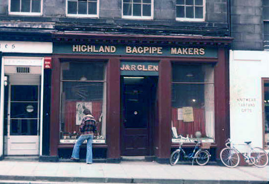 Man standing in front of J&R Glen Highland Bagpipe Makers shop, 1970s